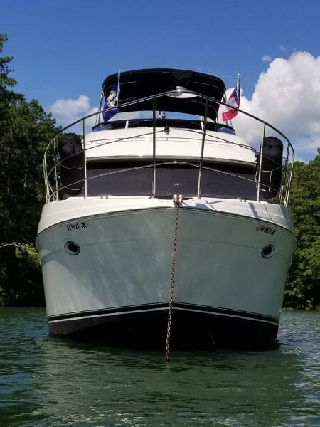 2004 Carver 360 Sport Sedan yacht anchored on a sunny day, surrounded by lush greenery.