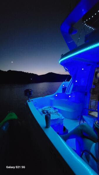 2004 Carver 360 Sport Sedan with blue LED lights on a serene lake at dusk.