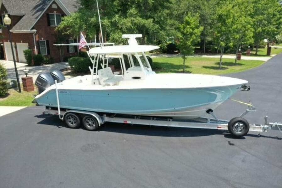 2021 Cobia 301 Center Console boat on trailer, parked in residential area.