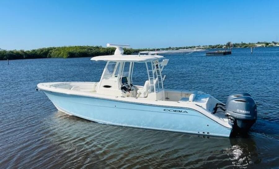 2021 Cobia 301 Center Console boat on calm water, featuring a sleek design and Yamaha engine.