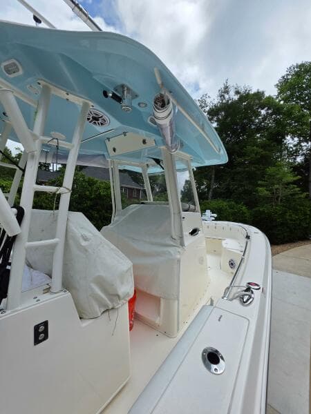2021 Cobia 301 Center Console boat with blue canopy, docked outdoors.