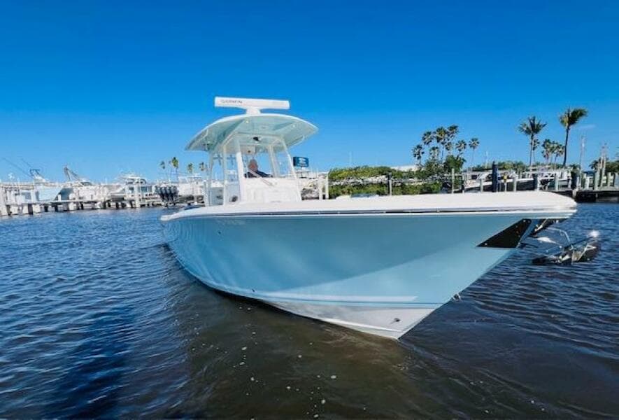 2021 Cobia 301 Center Console boat on water, clear blue sky, palm trees in background.