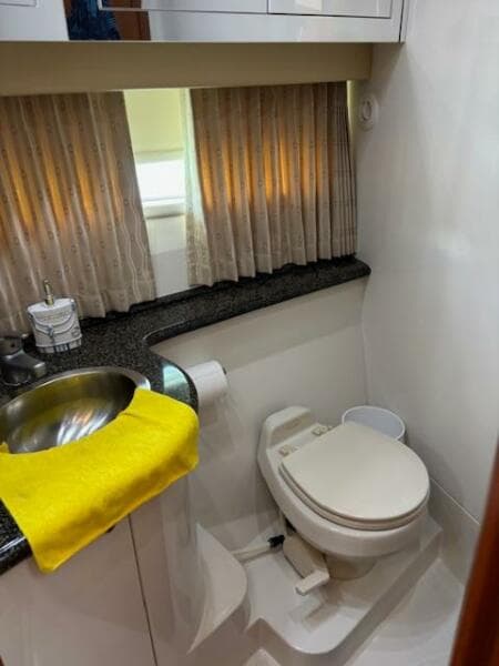 2006 Carver 43 Motor Yacht bathroom with sink, toilet, and window with curtains.