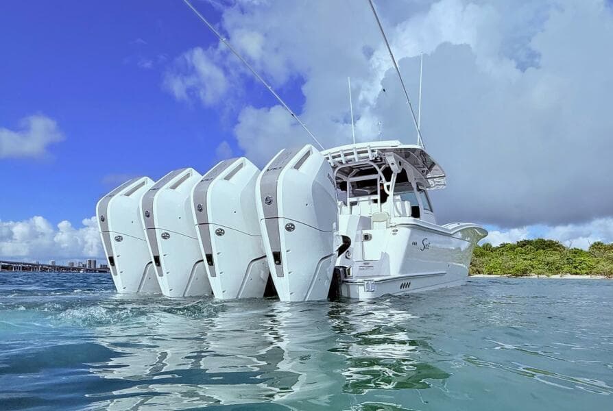 2024 Scout 400 LXF boat with multiple engines on water, under a clear blue sky.