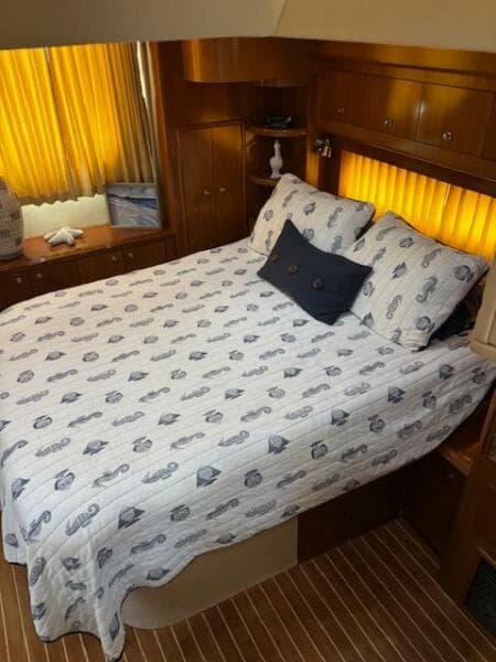 Cozy bedroom in 2006 Carver 43 Motor Yacht with nautical-themed bedding and warm lighting.