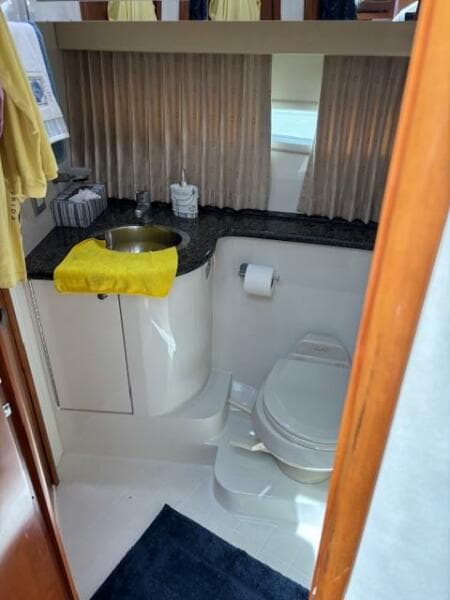 Bathroom interior of 2006 Carver 43 Motor Yacht with sink, toilet, and yellow towel.