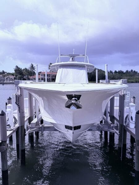 2024 Scout 400 LXF boat docked, front view with water and cloudy sky background.