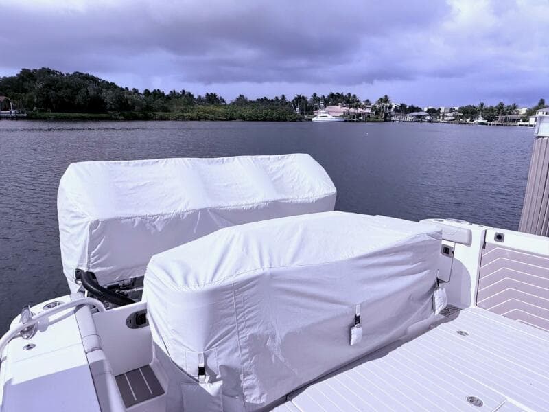 2024 Scout 400 LXF boat with covered engines docked by a scenic waterfront.
