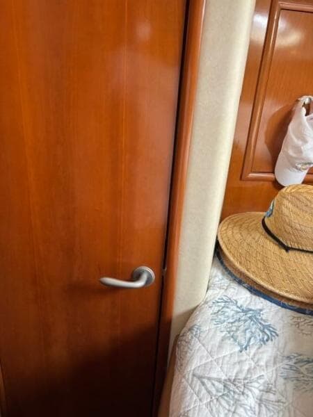 Interior of 2006 Carver 43 Motor Yacht with wooden door and straw hat on bed.