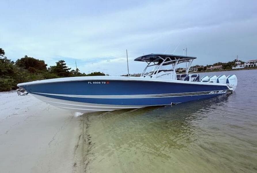 2022 Nor-Tech 390 Sport Center Console boat beached on sandy shore, blue hull, calm waters.
