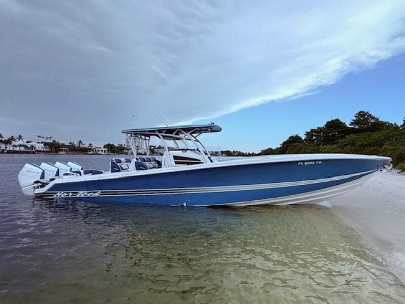 2022 Nor-Tech 390 Sport Center Console boat on sandy shore, under a cloudy sky.