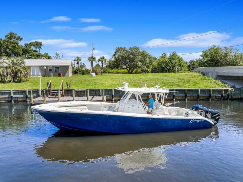 2015 Yellowfin 39 boat on calm water near a grassy shoreline.