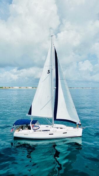 2015 Beneteau Oceanis 45 sailing on calm blue waters under a cloudy sky.
