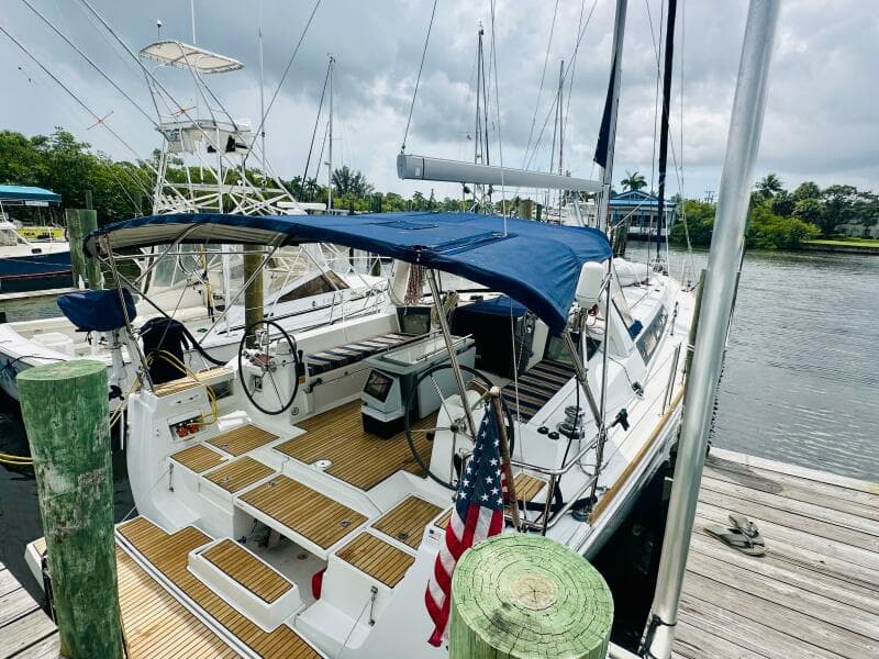 2015 Beneteau Oceanis 45 sailboat docked, featuring a blue canopy and wooden deck.