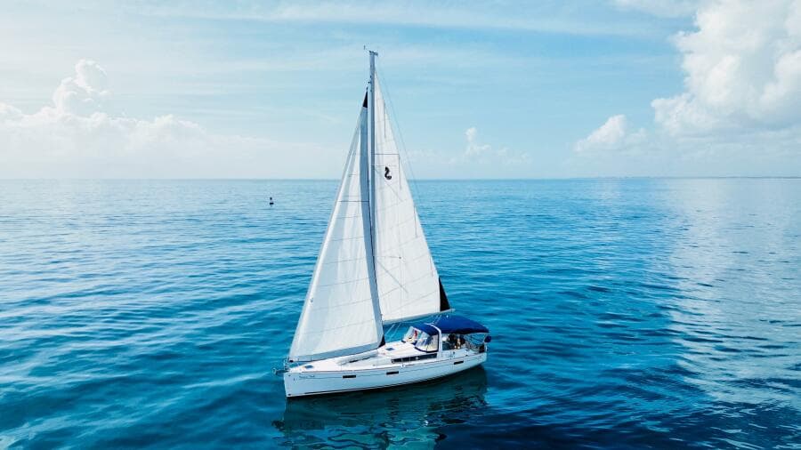 Sailing yacht Beneteau Oceanis 45, 2015 model, gliding on calm blue sea under clear sky.