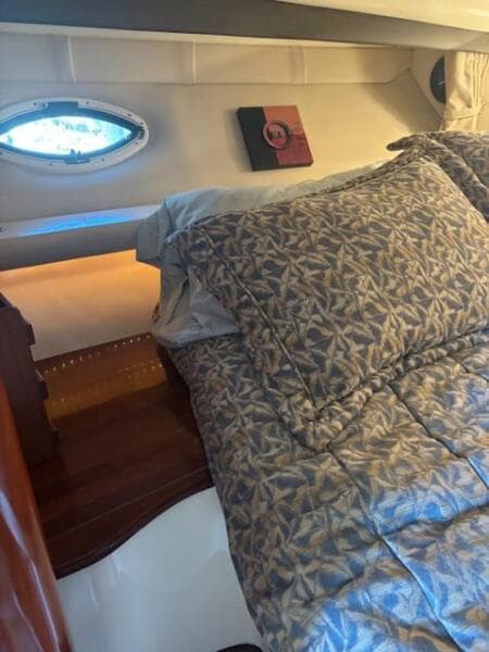 Cozy cabin interior of 2007 Monterey 350 Sport Yacht with patterned bedding and porthole window.