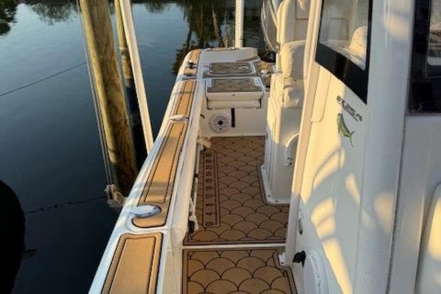 2018 Sea Hunt BX 25 FS boat deck with custom flooring, docked by calm water.