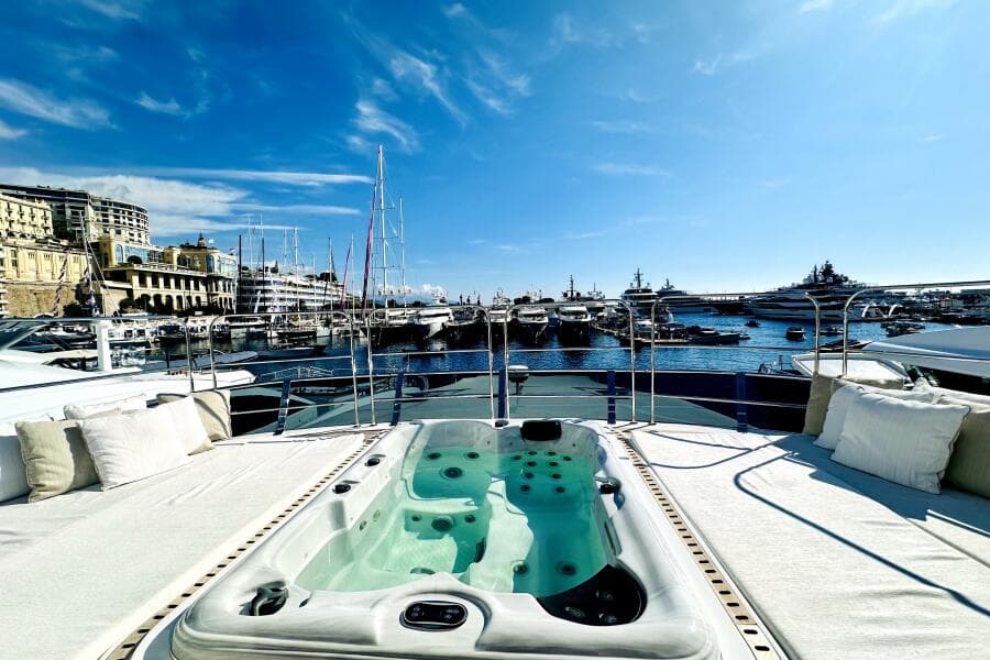 Luxurious 2023 Majesty 120 yacht with jacuzzi, docked in a scenic marina under a clear blue sky.
