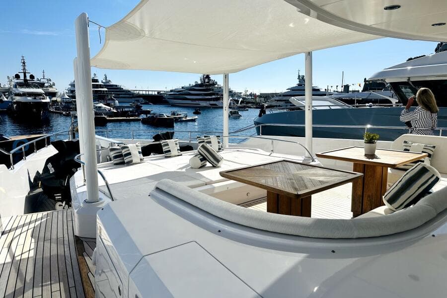 Luxurious 2023 Majesty 120 yacht deck with elegant seating, overlooking marina filled with yachts.