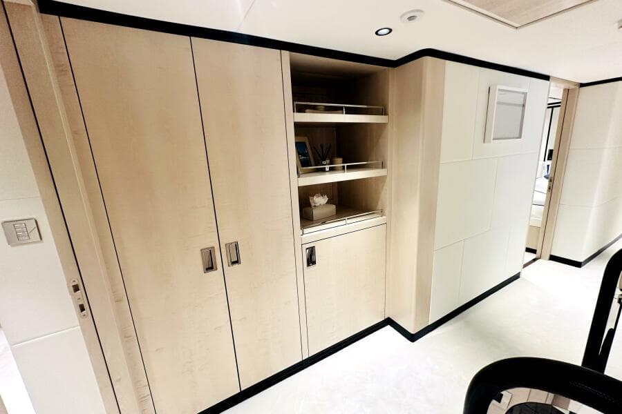 Modern interior of 2023 Majesty 120 yacht with sleek wooden cabinetry and open shelving.