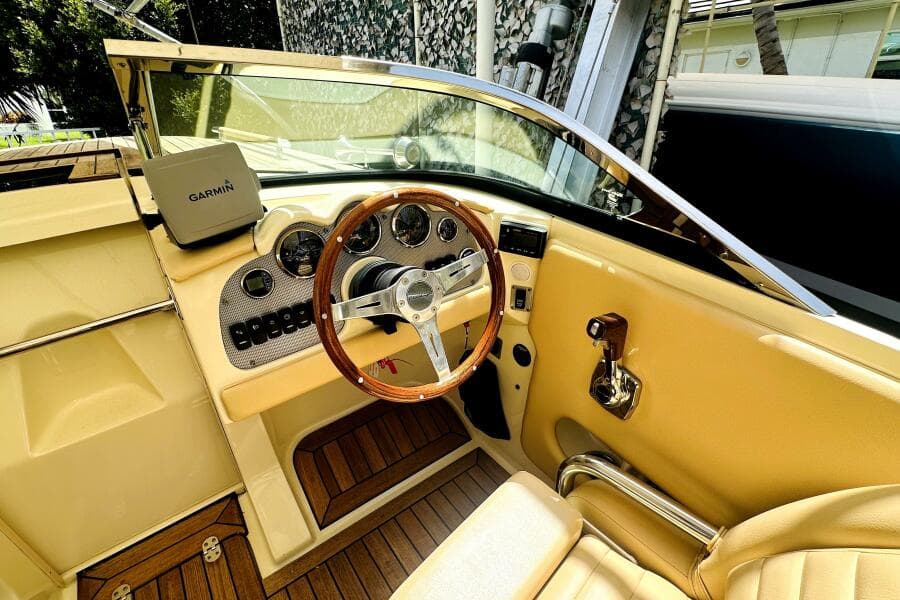 2013 Chris-Craft Corsair 22 cockpit with Garmin navigation, wooden steering wheel, and beige interior.