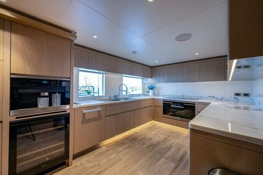 Modern kitchen interior on 2020 Majesty 140 yacht, featuring sleek cabinetry and appliances.