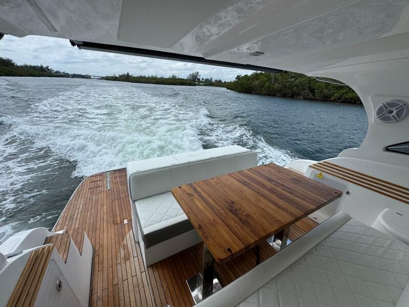 Luxurious 2025 Real 40 HT yacht interior with wooden table, cruising on a scenic waterway.