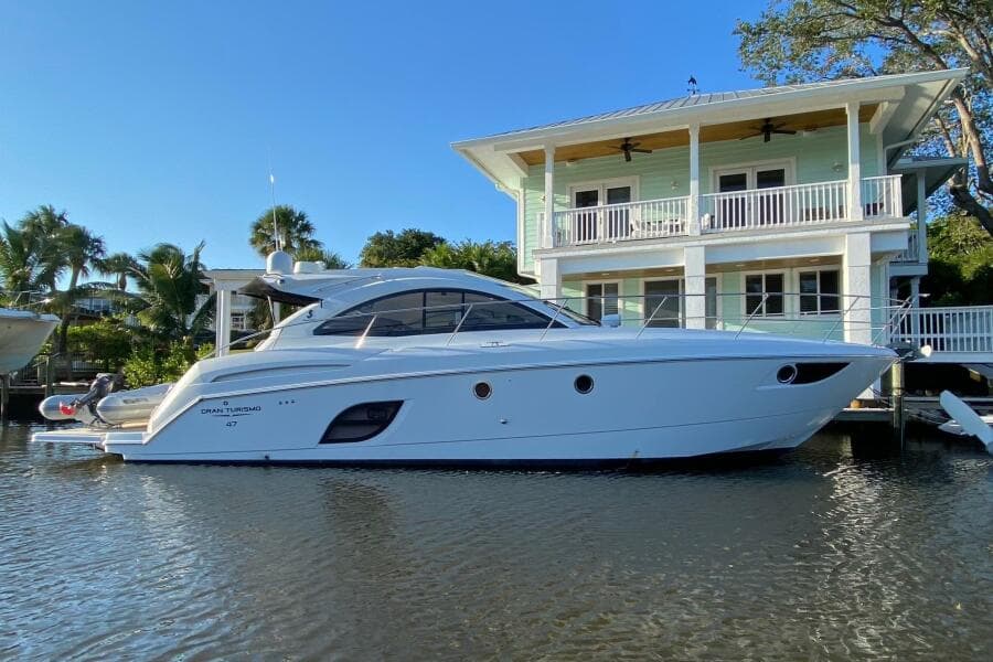 2014 Beneteau Gran Turismo 44 yacht docked by a waterfront house.