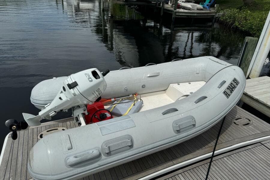 Inflatable boat with outboard motor docked beside a Beneteau Gran Turismo 44, 2014 model.