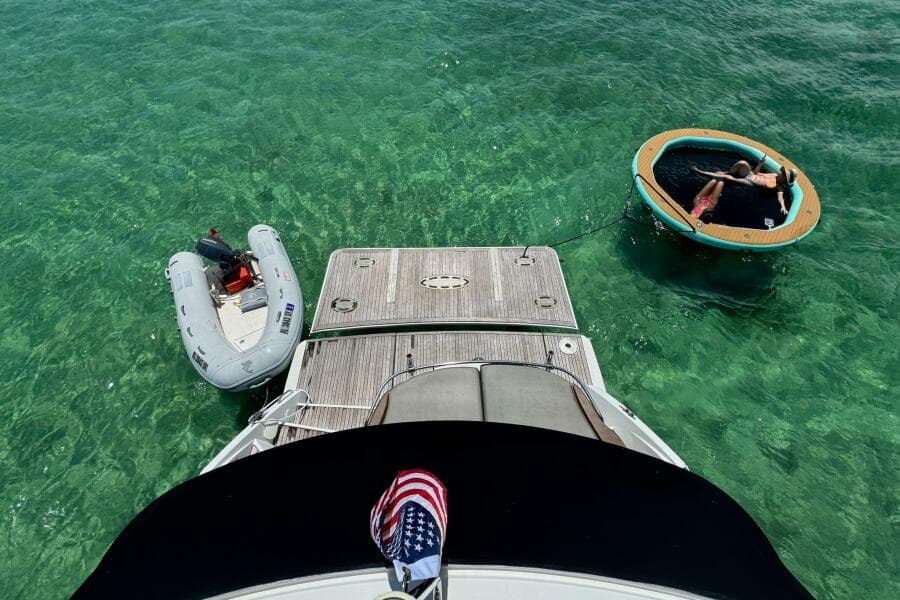 Beneteau Gran Turismo 44 yacht with inflatable boat and floating lounge in clear water.