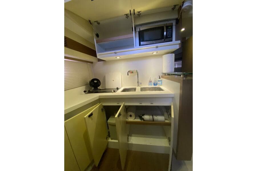 Compact kitchen in 2014 Beneteau Gran Turismo 44 yacht with microwave, sink, and storage.