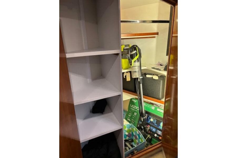 Storage area inside 2004 Carver 466 Motor Yacht with shelves and cleaning equipment.