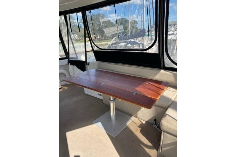 Interior of 2004 Carver 466 Motor Yacht with wooden table and marina view.