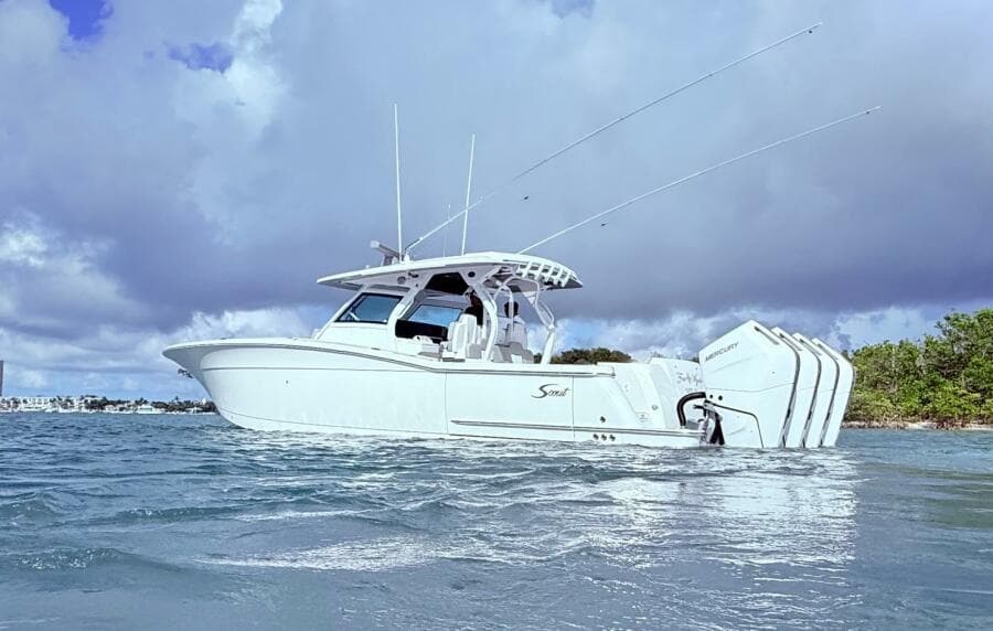 2024 Scout 400 LXF boat on water with triple Mercury engines, under cloudy sky.